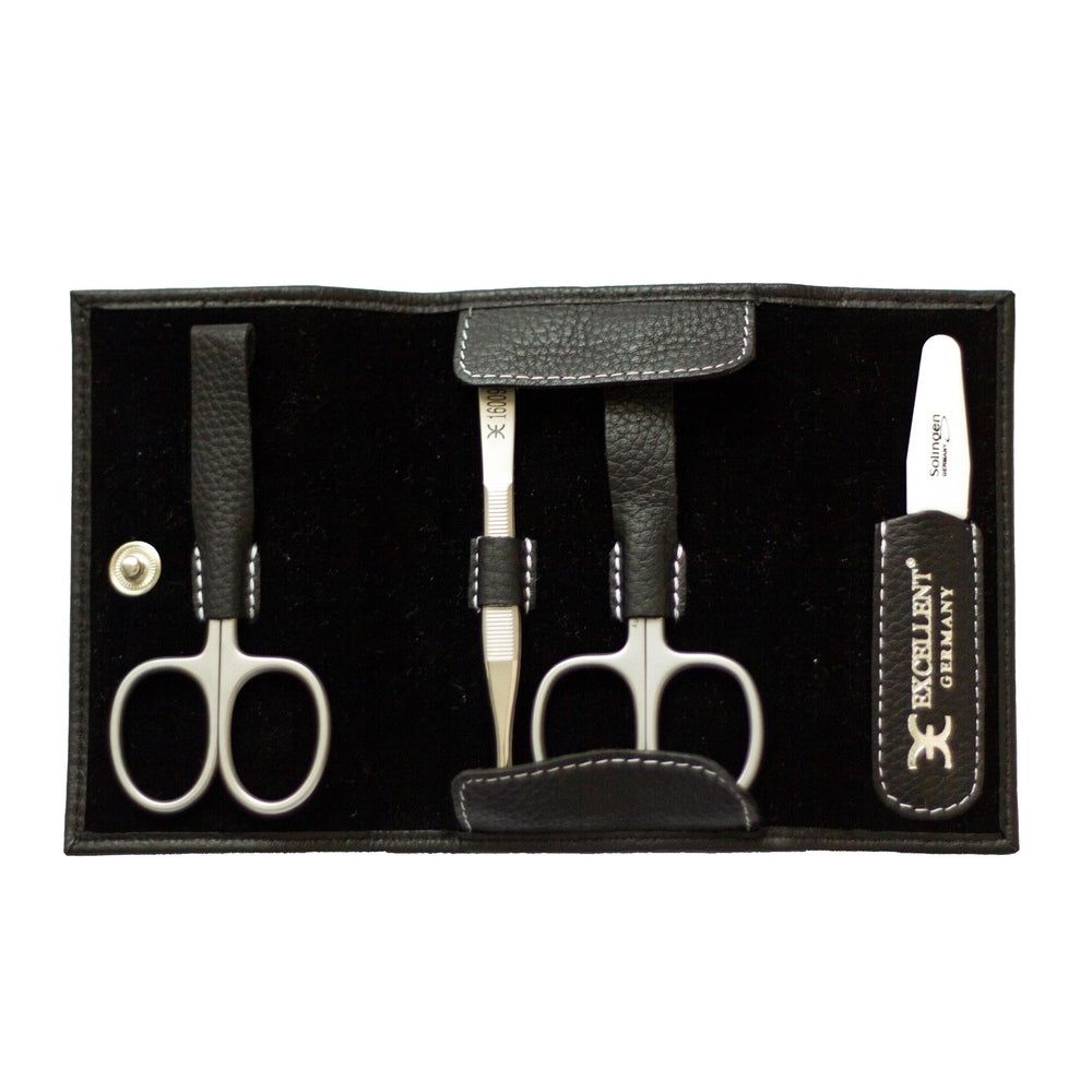 Geöffnetes Maniküre-Etui. Enthält Schere, Pinzette, Nagelfeile. Schwarzes Leder, weiße Nähte. Logo EXCELLENT.