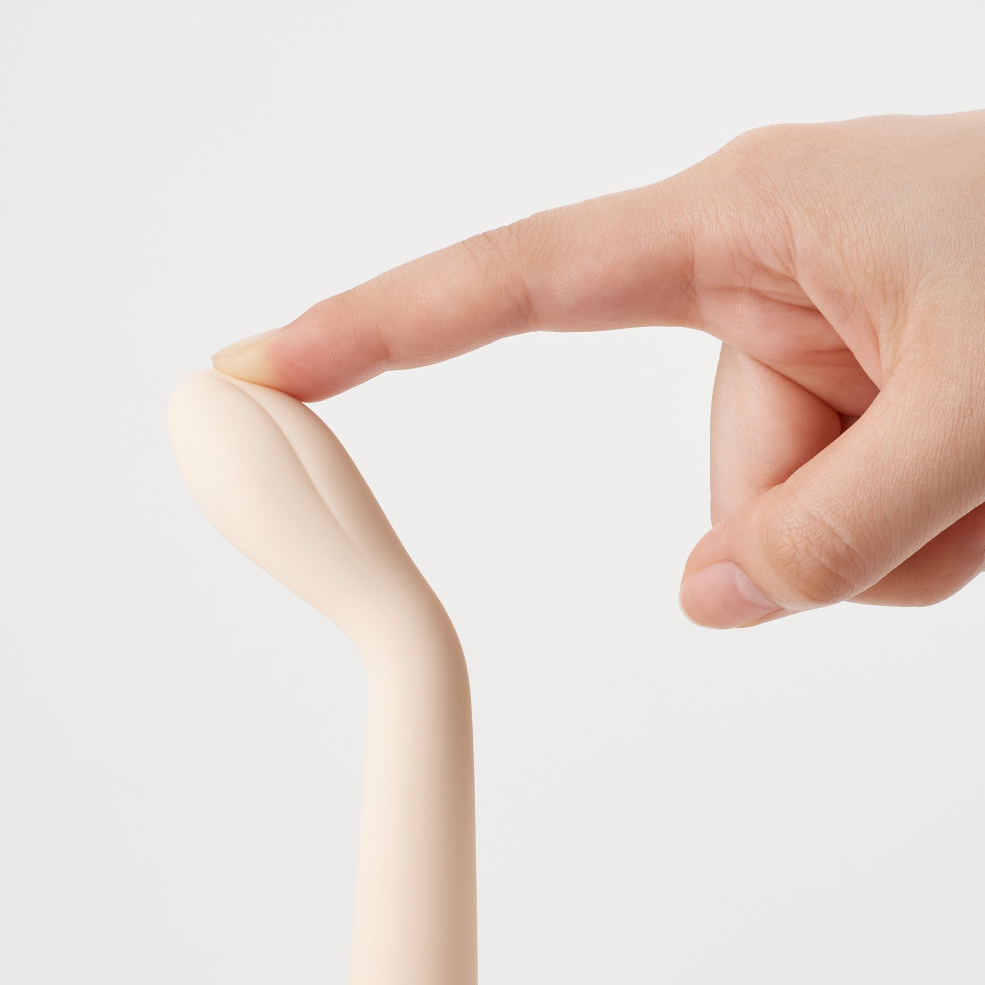 Nahaufnahme eines beigefarbenen Vibrators. Spitze wird mit Finger berührt.