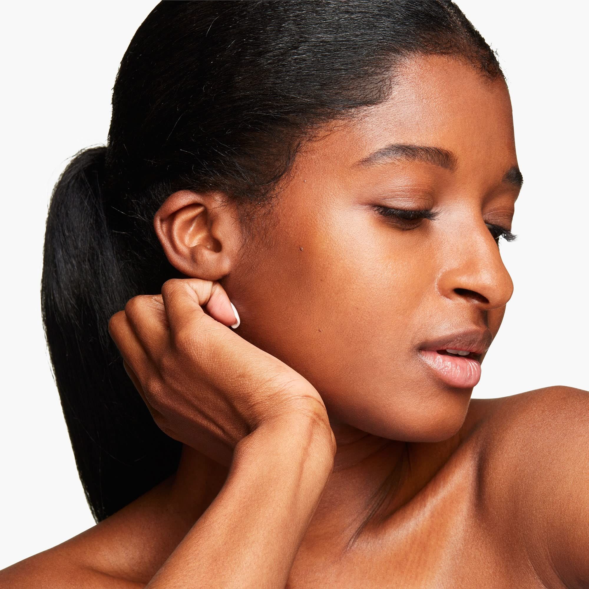 Porträt einer Frau mit dunklem Haar. Blick nach unten, Hand am Hals.