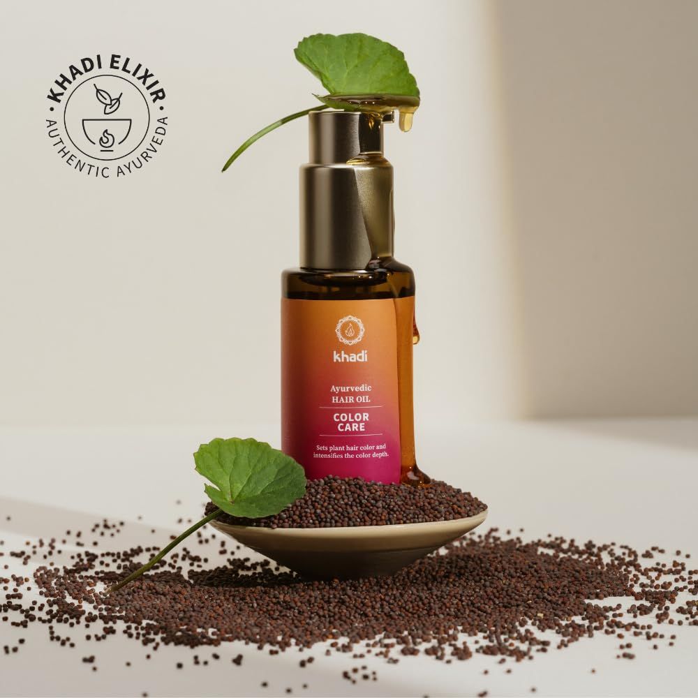 Braune Glasflasche mit goldenem Pumpkopf. Etikett mit Produktbezeichnung und Logo. Tropfendes Öl. Blätter und Samen.