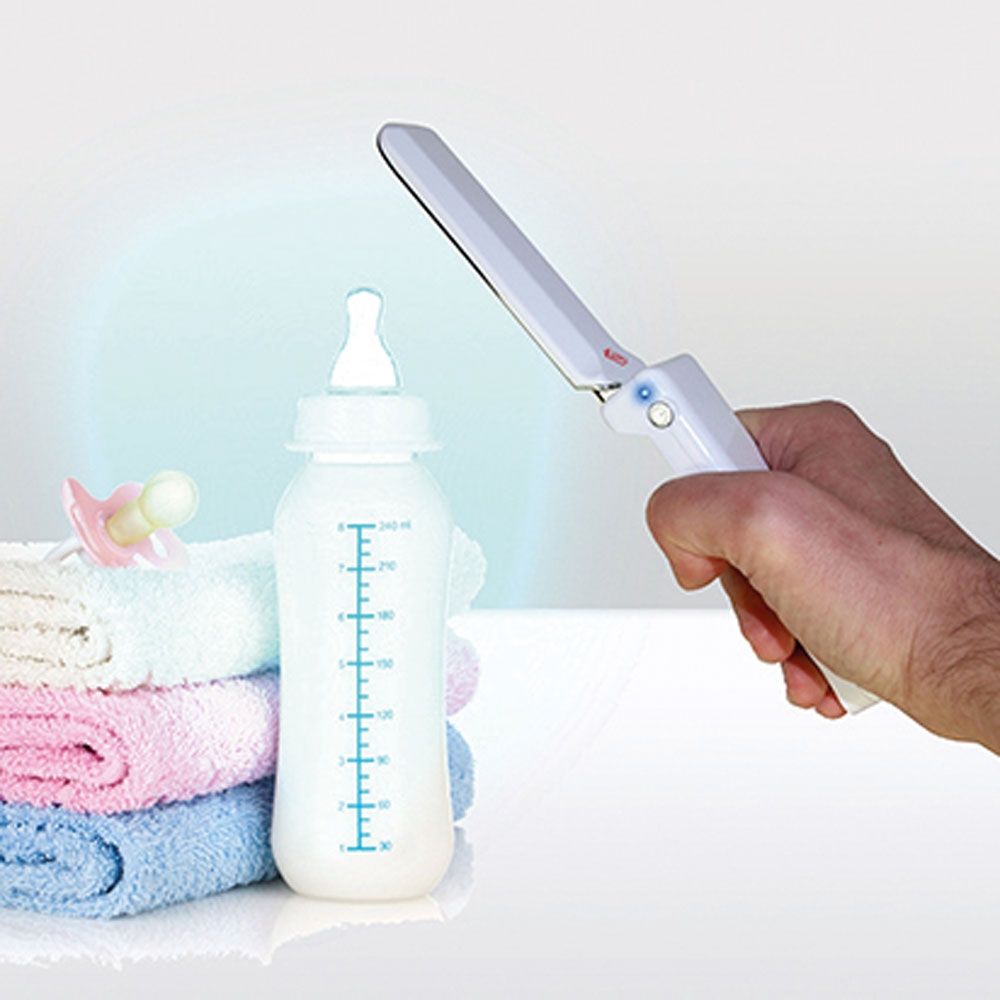 Weißes UV-C-Desinfektionslicht über einer Babyflasche. Blaue Lichtquelle. Hand hält das Gerät.