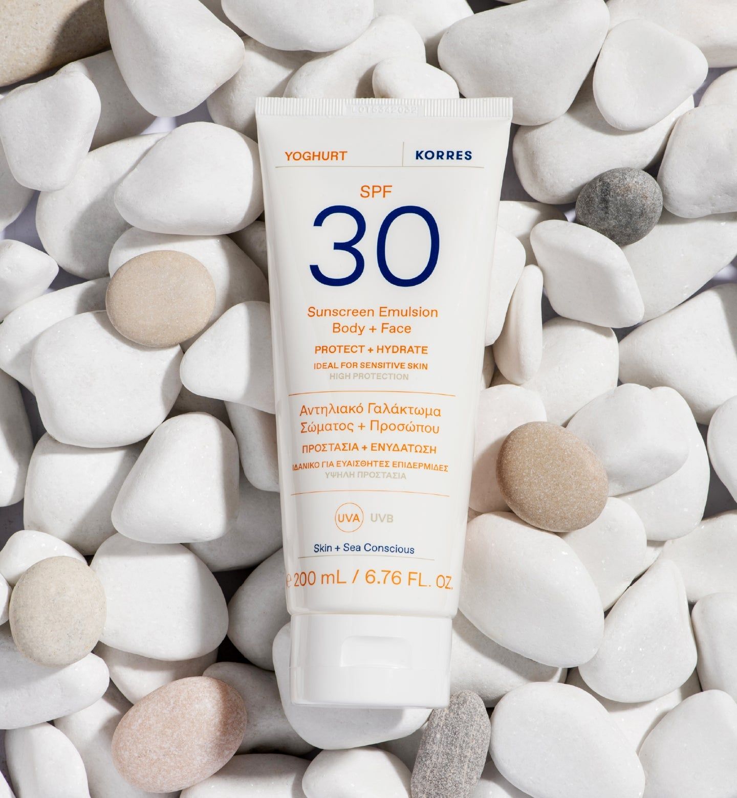 Weiße Tube mit blauer und orangefarbener Schrift. Auf weißen Steinen. Produktname: Yoghurt Sonnenschutz-Emulsion SPF 30.