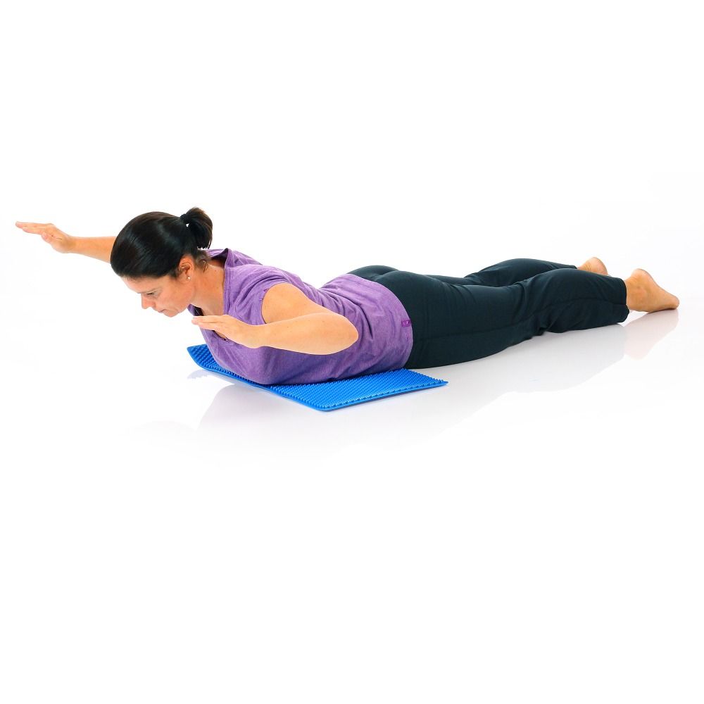 Person liegt auf blauer Matte mit Noppen. Arme ausgestreckt. Matte unter dem Bauch. Helle Umgebung.