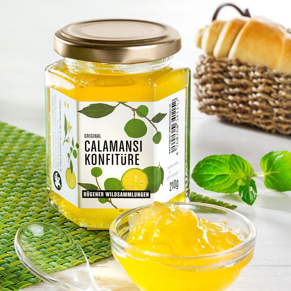 Glas mit Calamansi Konfitüre, Etikett mit Produktname und Illustrationen. Kleines Schälchen mit Konfitüre daneben.