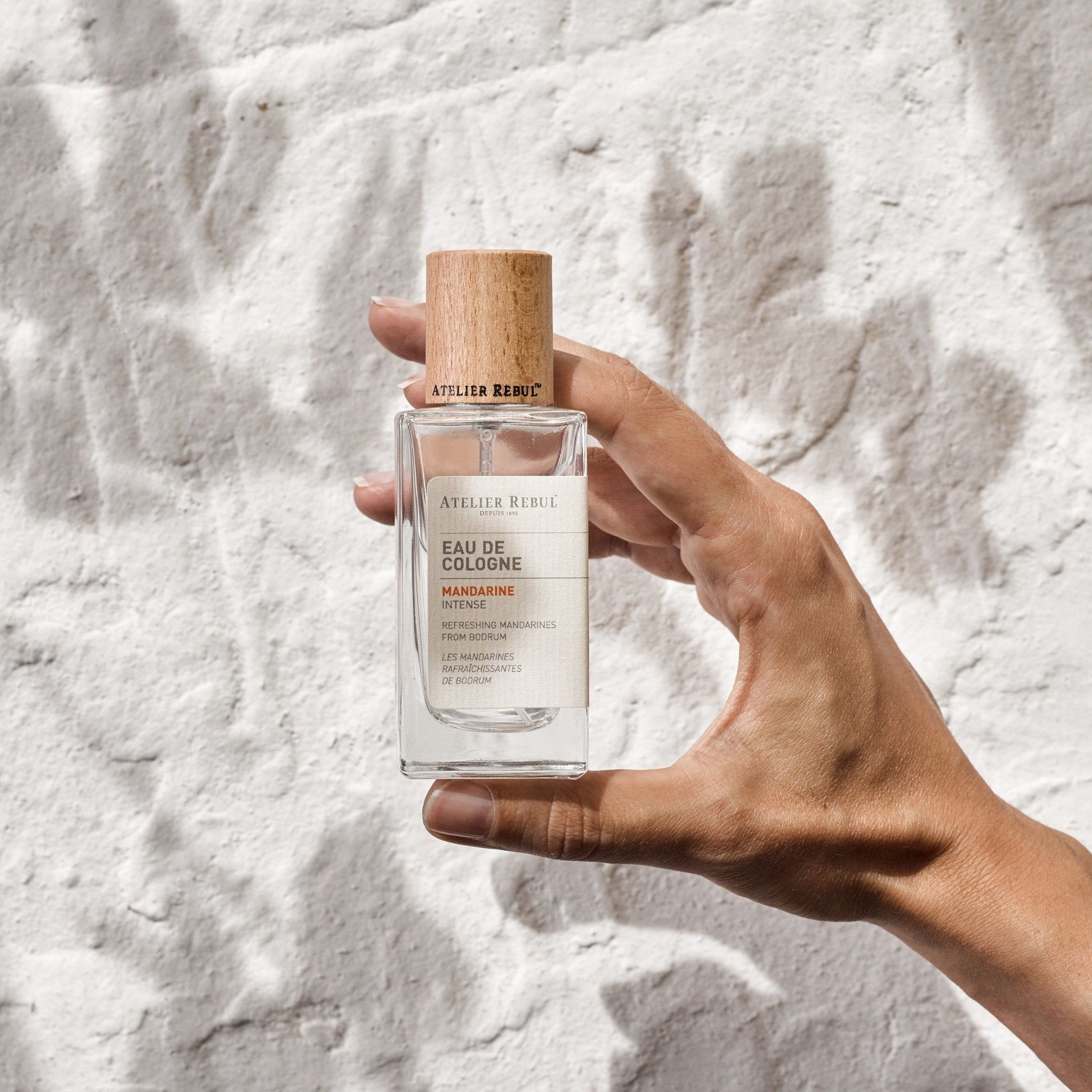 Glasflasche Atelier Rebul Mandarine Eau de Cologne mit Holzverschluss, gehalten in einer Hand.