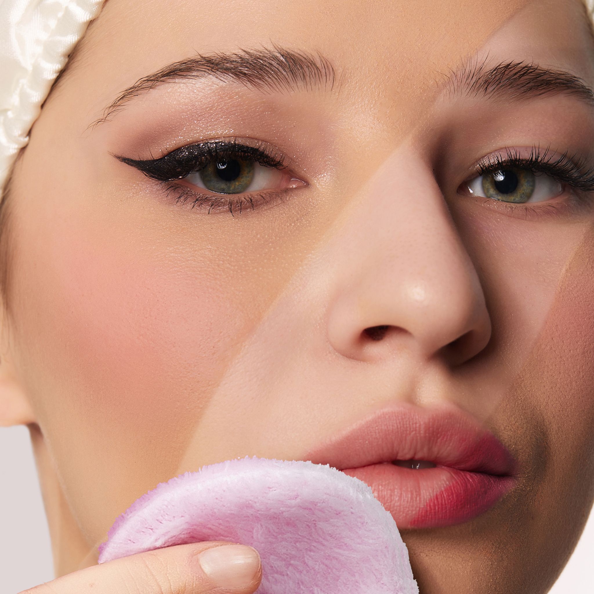 Frau mit Make-up und einem rosa Wattepad.