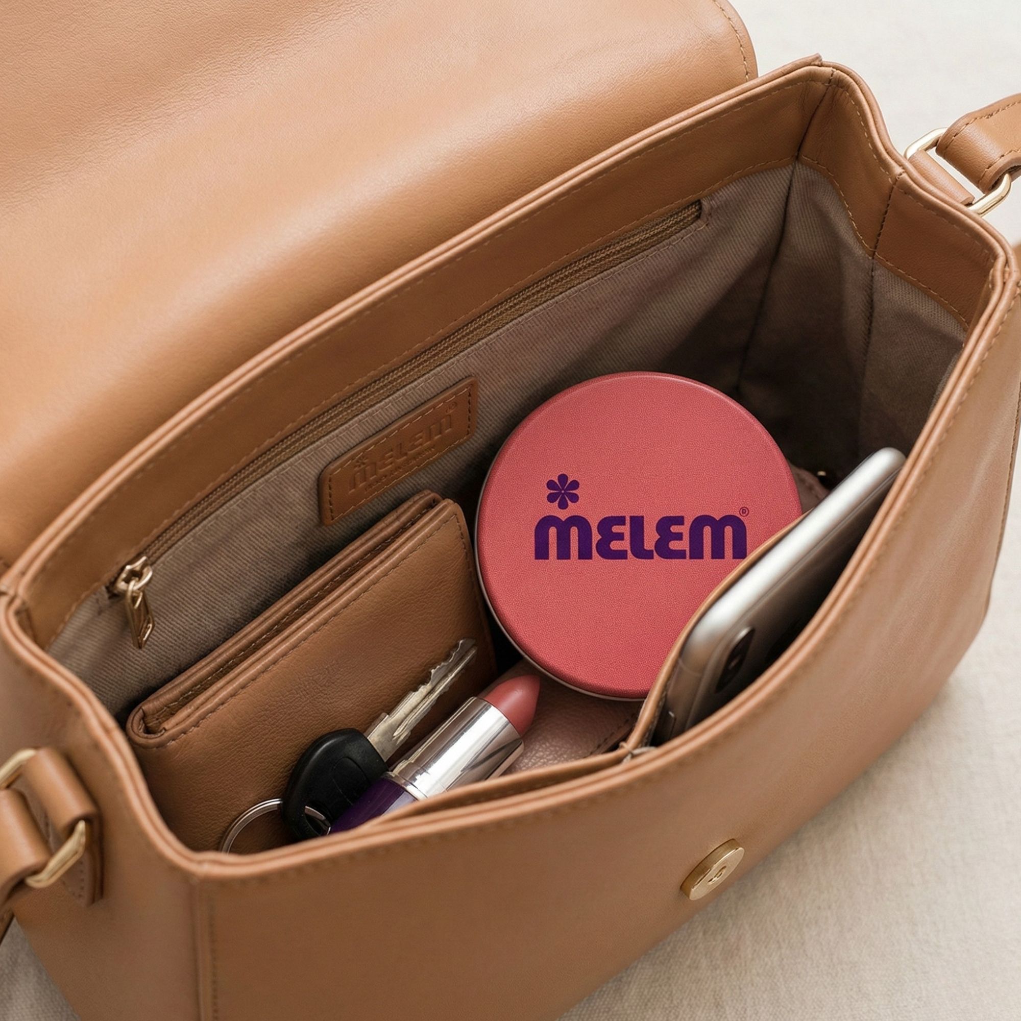 Offene Handtasche mit rotem Tiegel mit Produktlogo, Geldbörse, Handy und Schlüsseln.