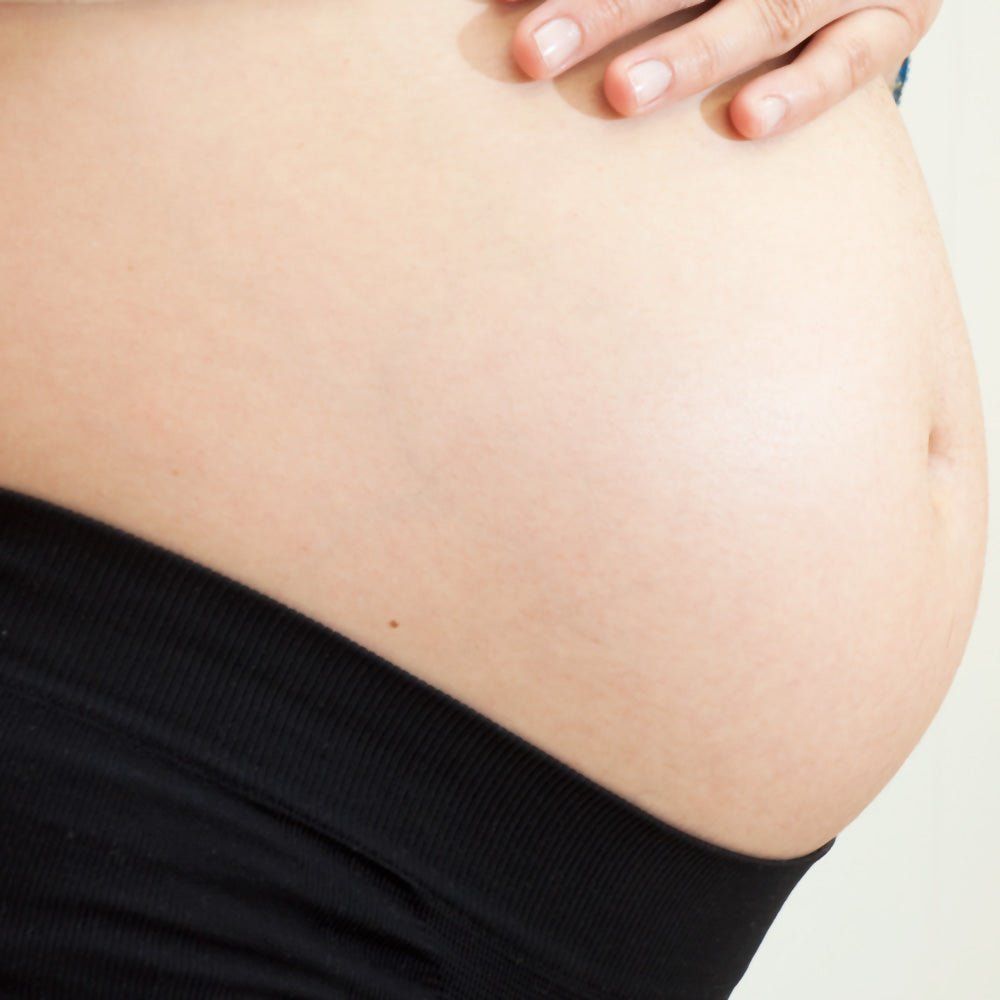 Schwarzer Stoff am Bauch. Schwangere Frau, Nahaufnahme des Bauches.