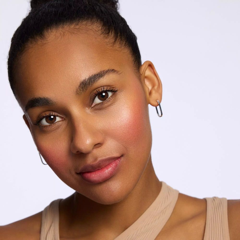 Porträt einer Frau mit dunkler Haut. Rouge auf den Wangen. Trägt Ohrringe.