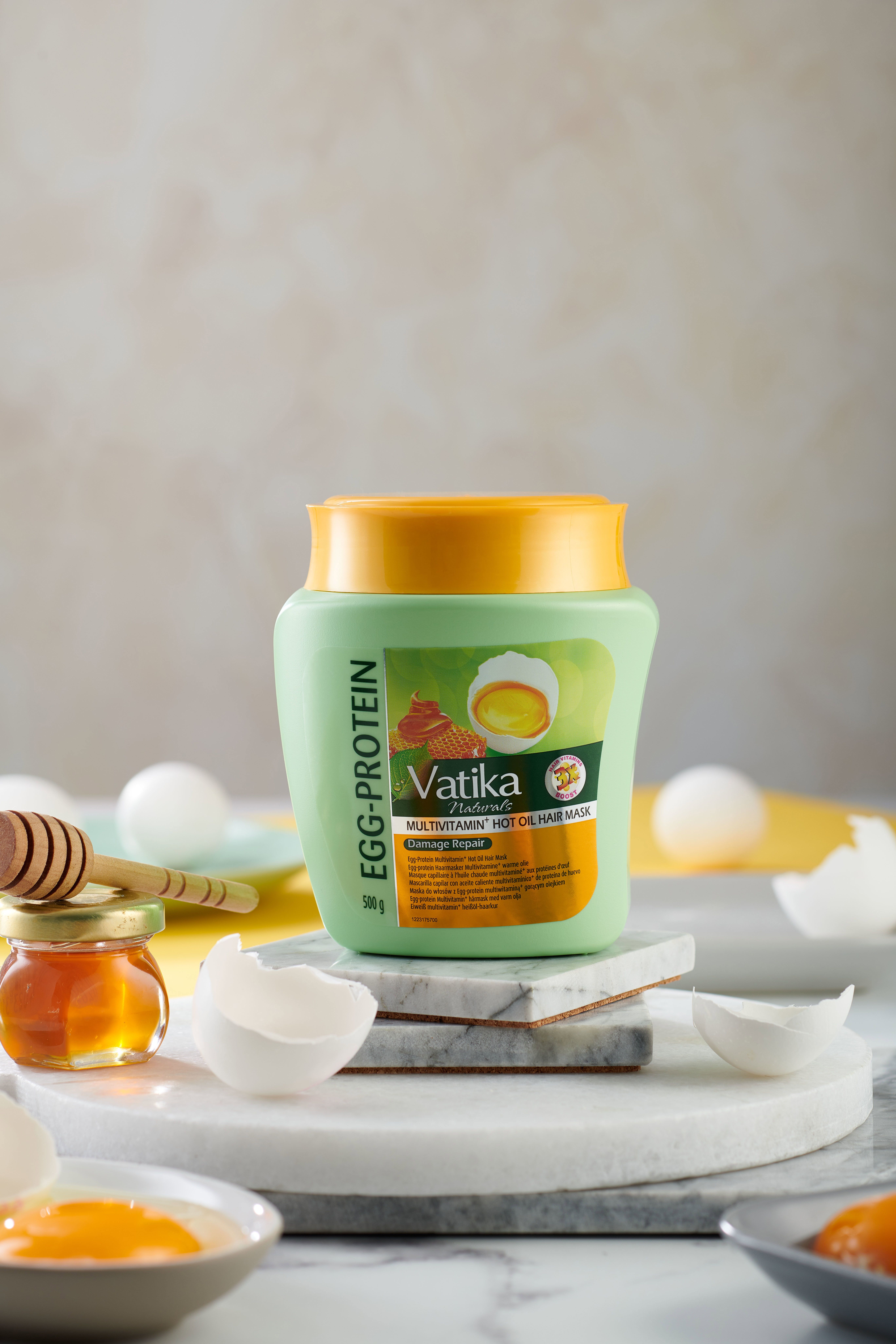 Grüne Haarmaske mit gelbem Deckel, Honigglas, Eierschalen. Text: Vatika Naturals, Egg-Protein, Multivitamin, Hot Oil Hair Mask, 500g.