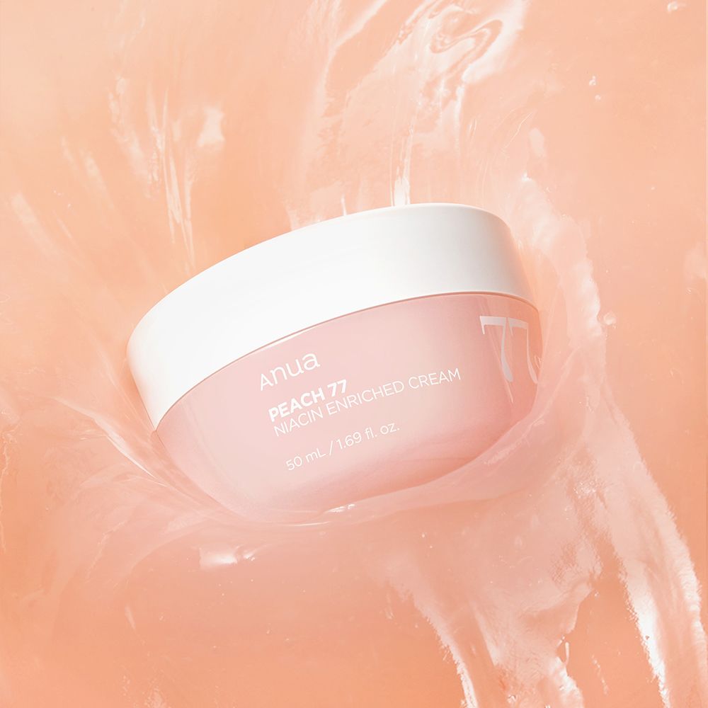 ANUA Peach 77% Niacin Enriched Cream in einem rosa Tiegel, der in einer cremigen, pfirsichfarbenen Flüssigkeit platziert ist.