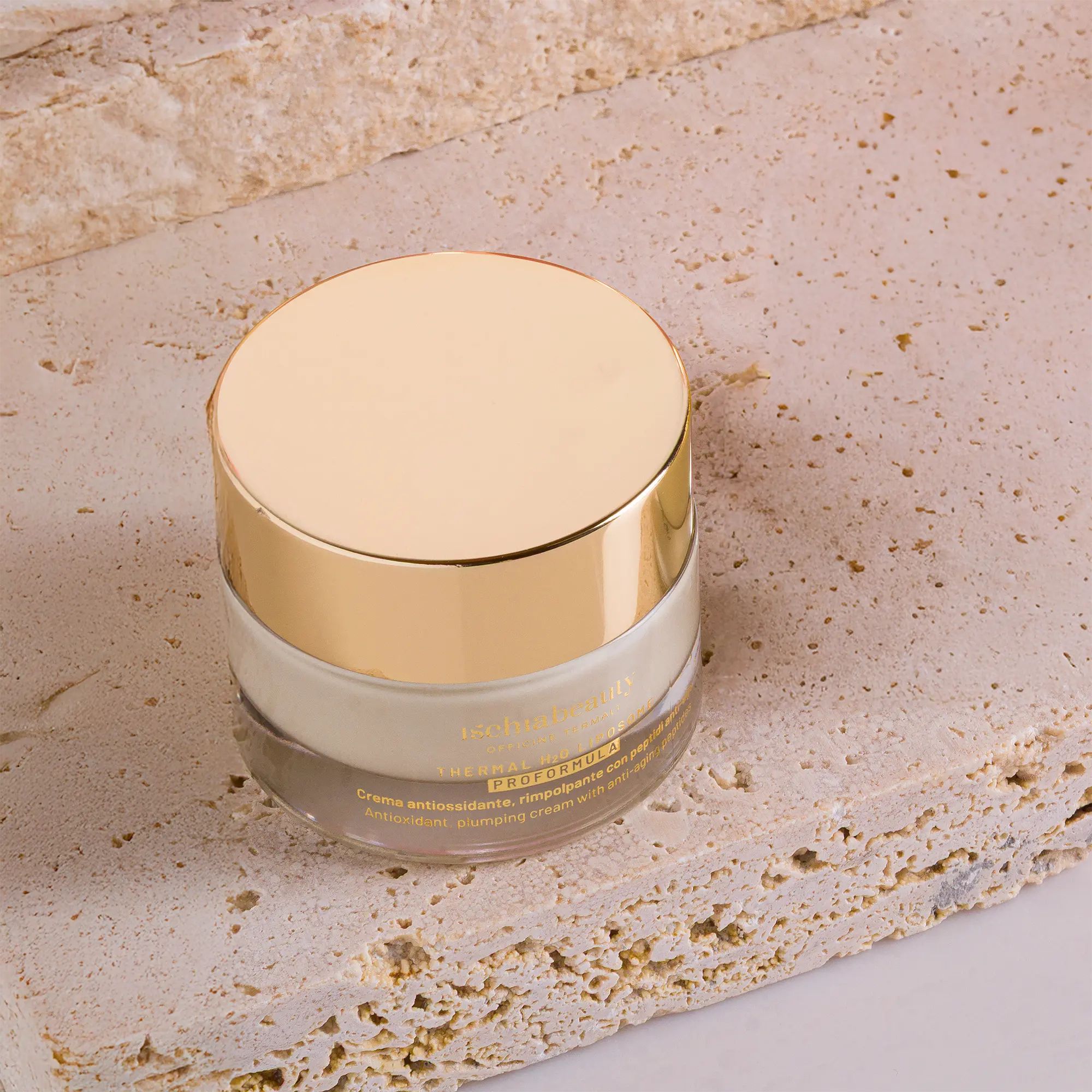 Cremebehälter mit goldenem Deckel. Auf Steinplatte. Sichtbare Produktbeschriftung. Transparenter Behälter.