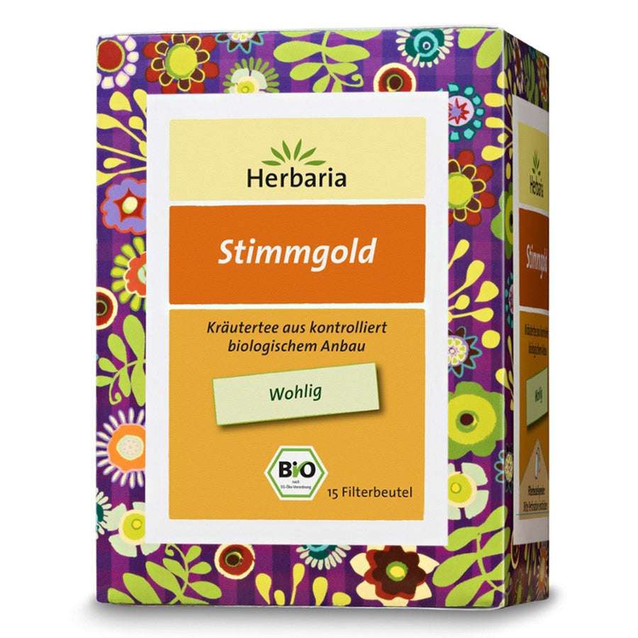 Verpackung von Herbaria Stimmgold Tee. Orangefarbener Schriftzug "Stimmgold" auf gelbem Grund. Bio-Siegel. 15 Filterbeutel.