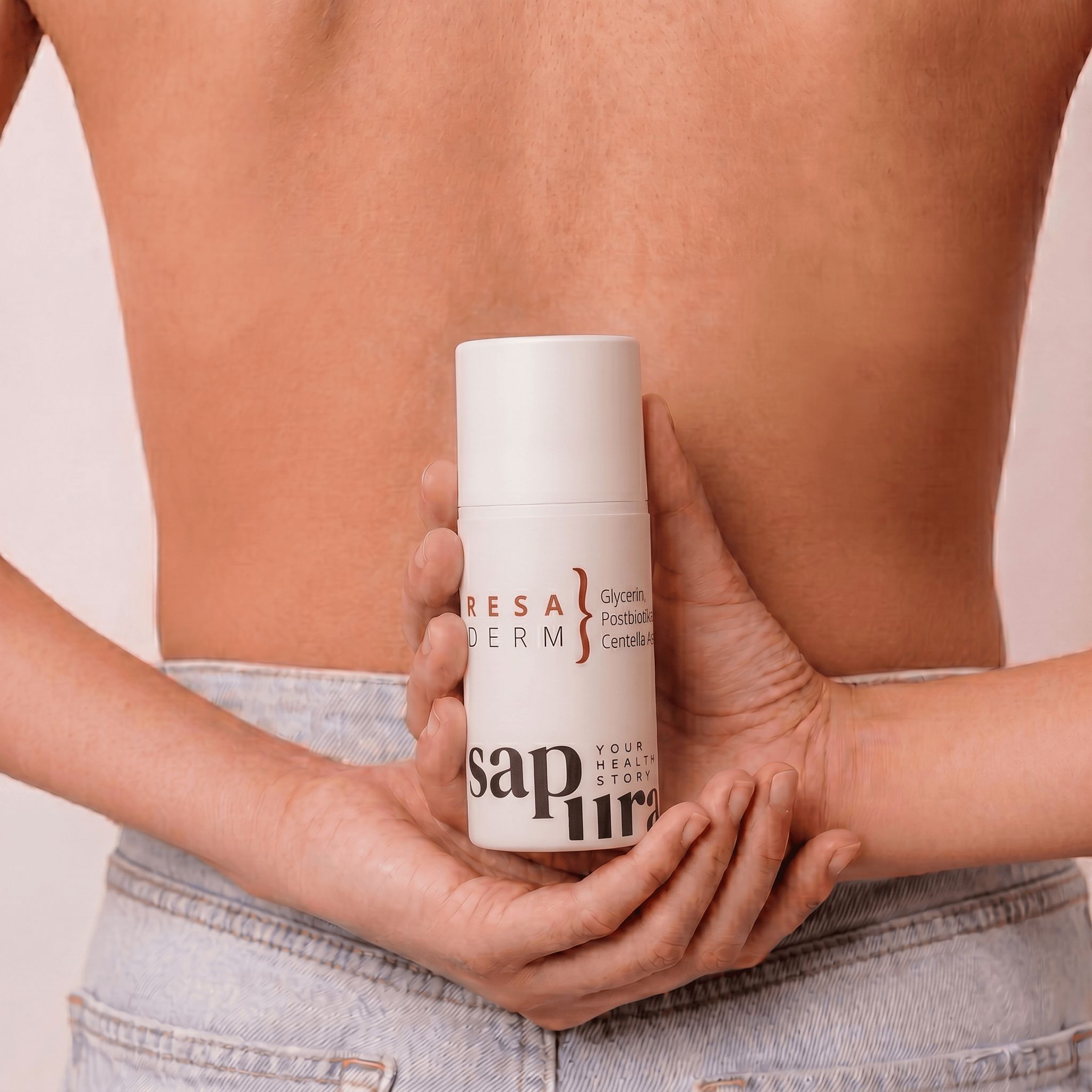Hände halten weiße Pumpflasche mit Rosacea Creme hinter dem Rücken einer Person.