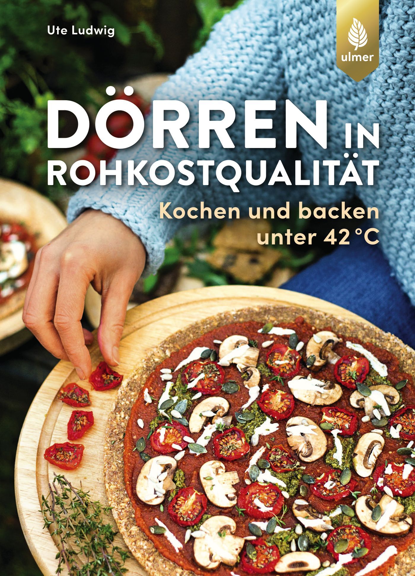 Buchcover: "Dörren in Rohkostqualität". Titel, Autorin Ute Ludwig. Pizza mit Tomaten und Pilzen auf Holzbrett. Kochbuch.