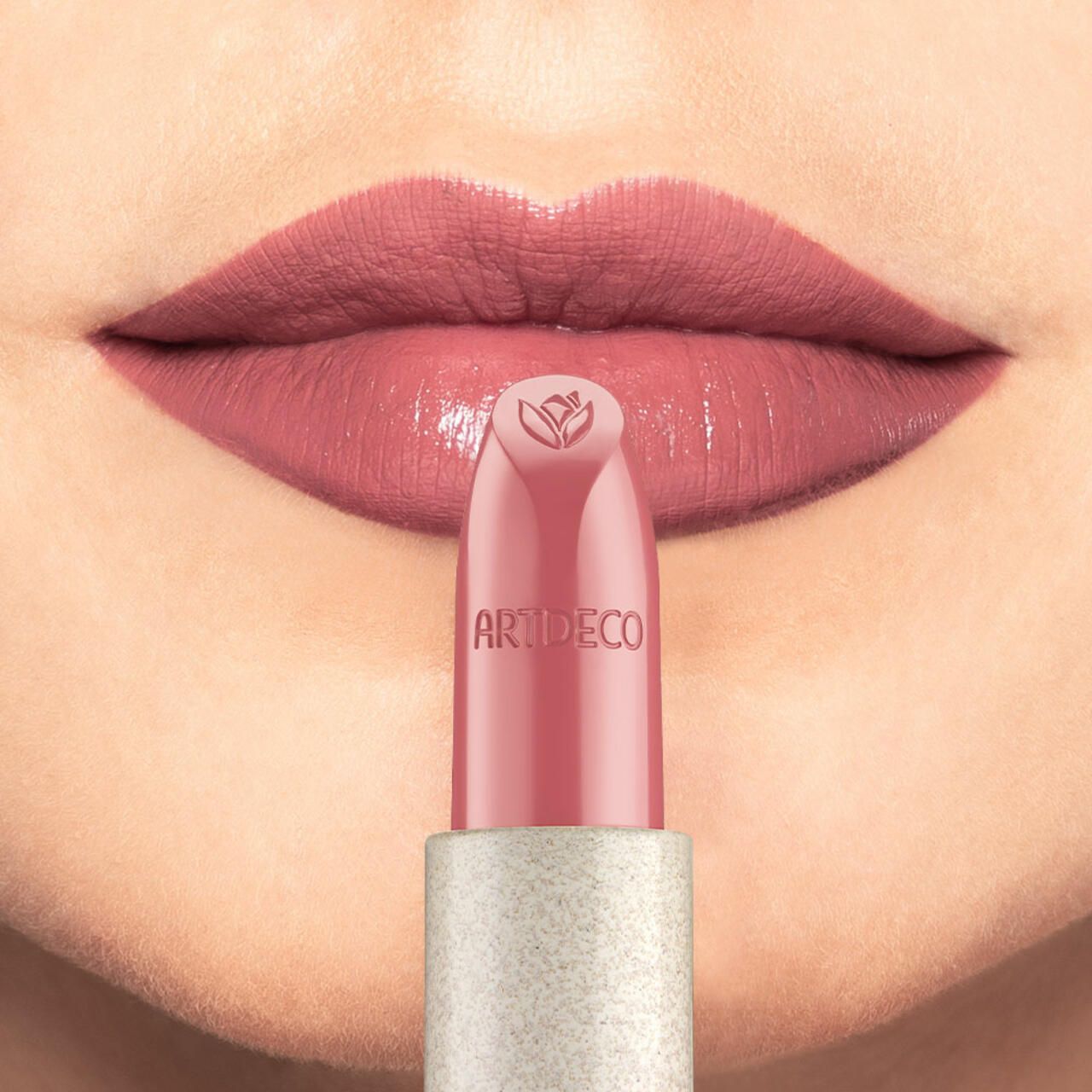 Lippen mit aufgetragenem rosa Lippenstift. Lippenstift mit Blütenmotiv und Artdeco-Logo wird aufgetragen.