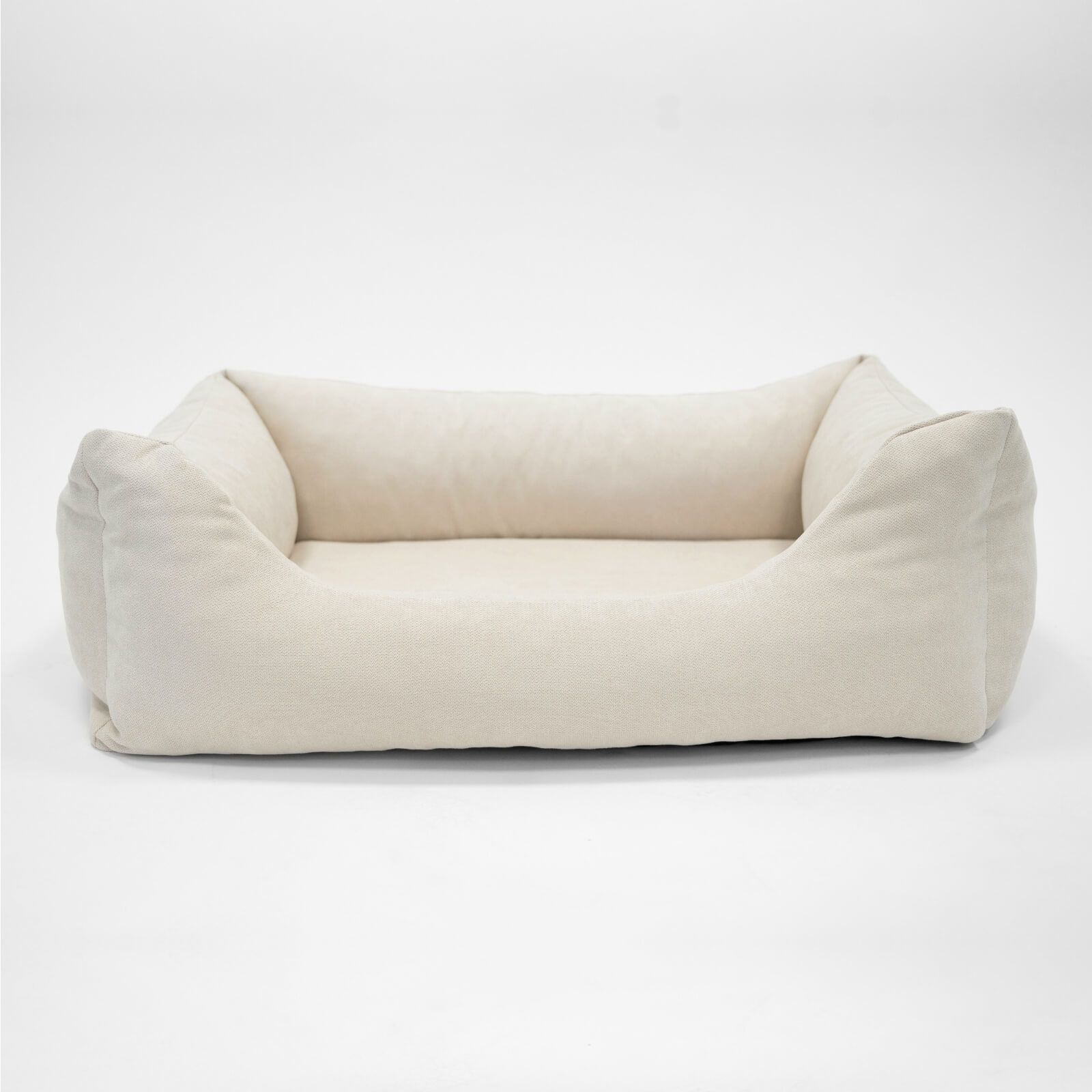 Beige Hundebett mit rechteckiger Form und erhöhten Seiten. Auf hellem Hintergrund.