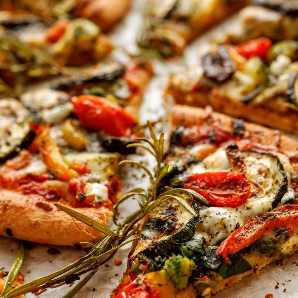 Pizza mit Gemüse und Kräutern. Aufgeschnittene Stücke. Nahaufnahme mit Rosmarinzweig.