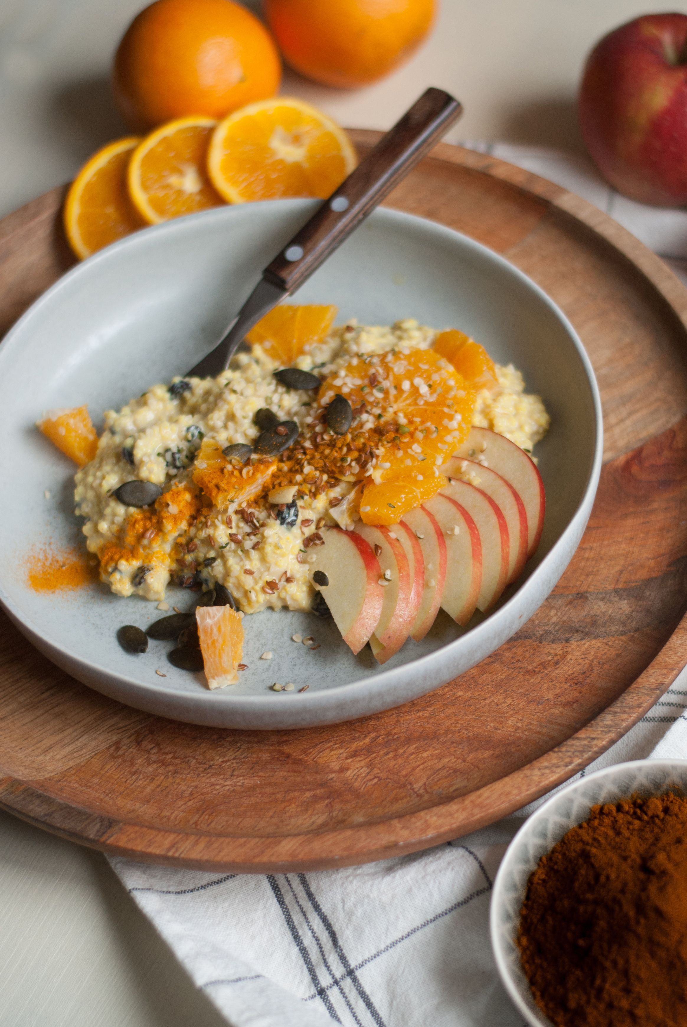 Porridge mit Orangen- und Apfelscheiben, Zimt und Kernen bestreut.
