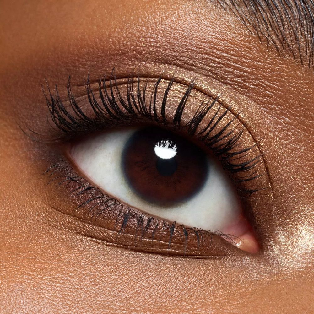 Nahaufnahme eines Auges mit brauner Iris und Wimperntusche. Hautton: dunkel.