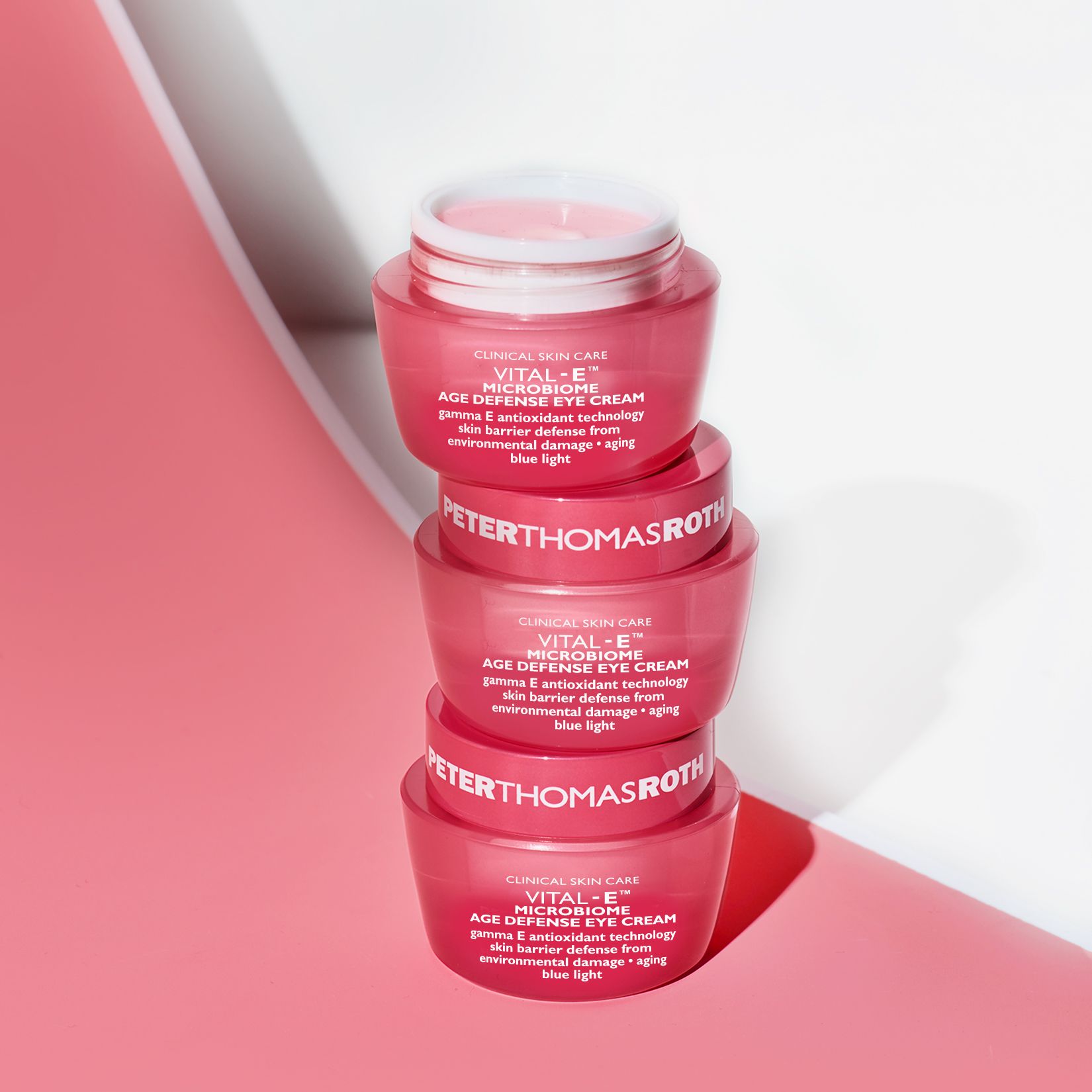 Vier rosa Tiegel gestapelt. Text: VITAL-E MICROBIOME AGE DEFENSE EYE CREAM. Aufschrift PETERTHOMASROTH. Auf rosa Hintergrund.