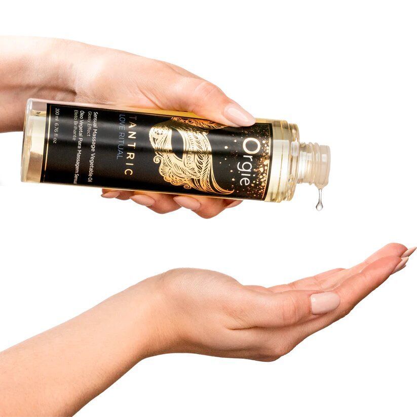 Eine Hand hält eine transparente Flasche, aus der Öl in die andere Hand tropft. Auf der Flasche steht "Orgie" und "Tantric Love Ritual".