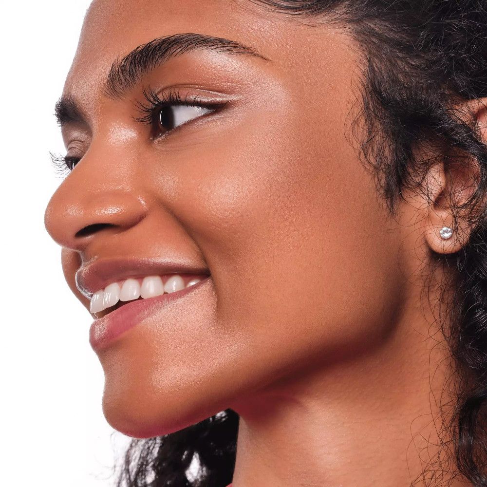 Porträt einer Frau mit gebräunter Haut. Sie lächelt. Deutlich sichtbare Wangenknochen.