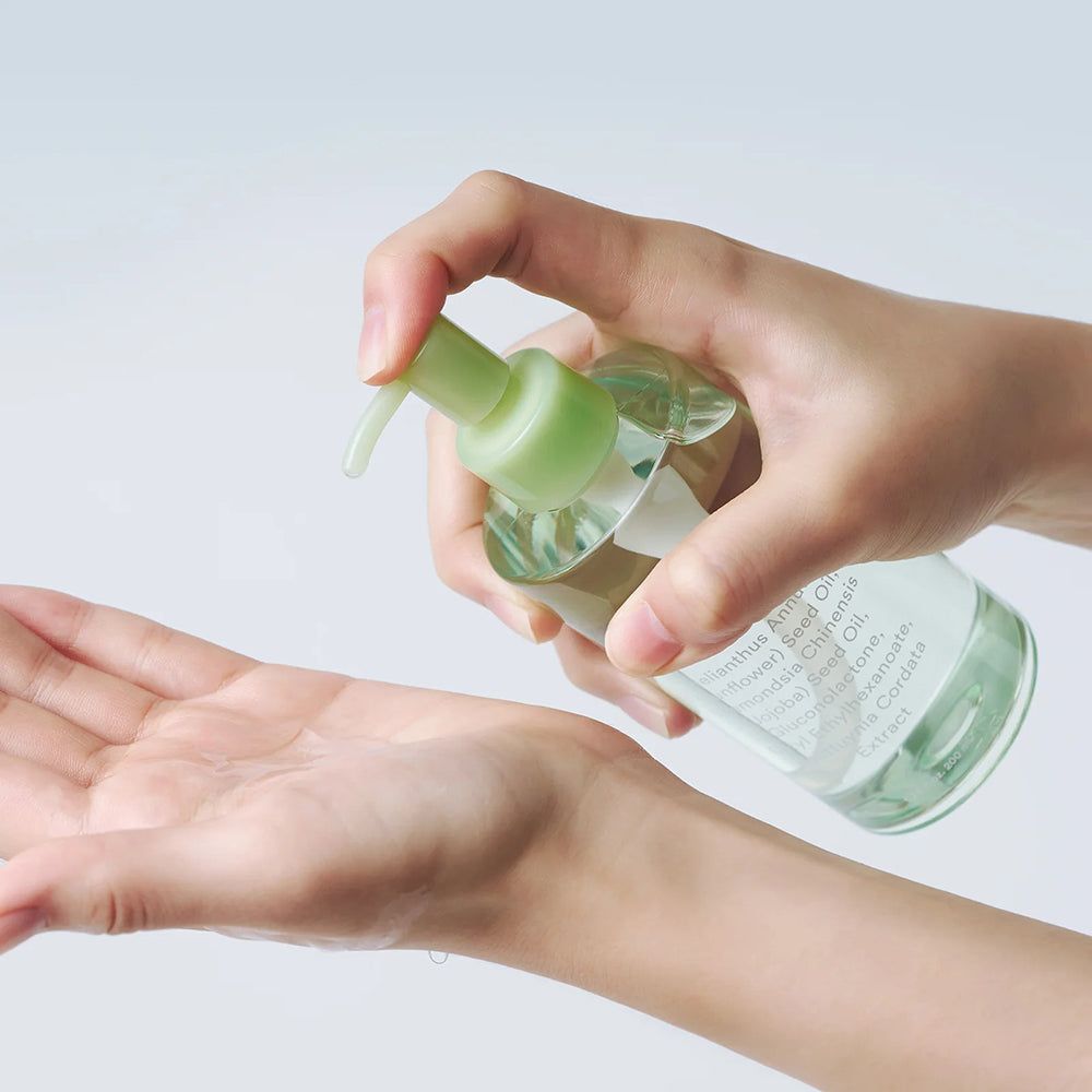 Hand drückt Pumpspender, um klares Öl in die andere Handfläche zu geben.