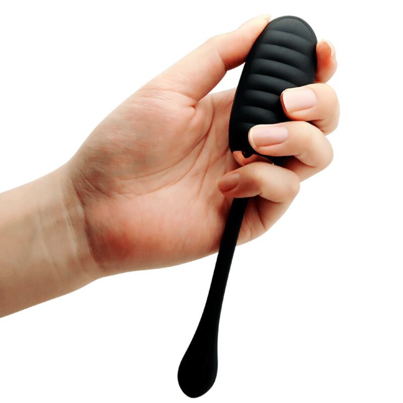 Hand hält schwarzes Vibrations-Ei. Geriffelte Oberfläche, langer Stiel.