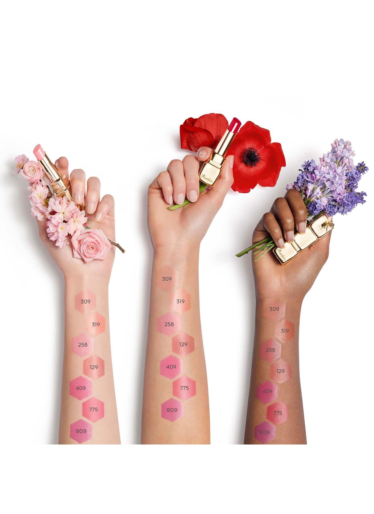 Drei Arme mit Lippenbalsam-Farben aufgetragen. Die Farben sind auf der Haut markiert. Blumen und Lippenbalsam-Stifte sind ebenfalls zu sehen.