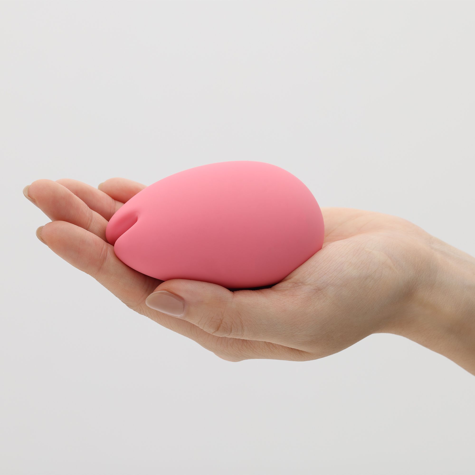 Rosa, tropfenförmiges Produkt in einer Handfläche. Auf hellem Hintergrund.