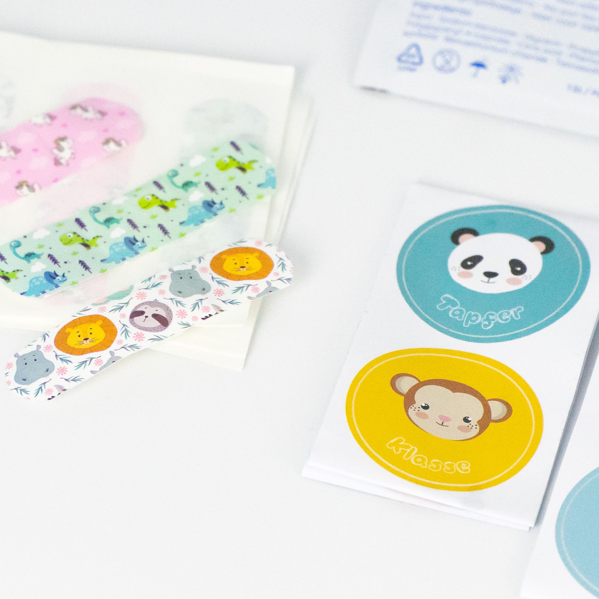 Nahaufnahme von Pflastern mit Tiermotiven und Aufklebern. Aufkleber mit Panda und Affe. Hintergrund weiß.