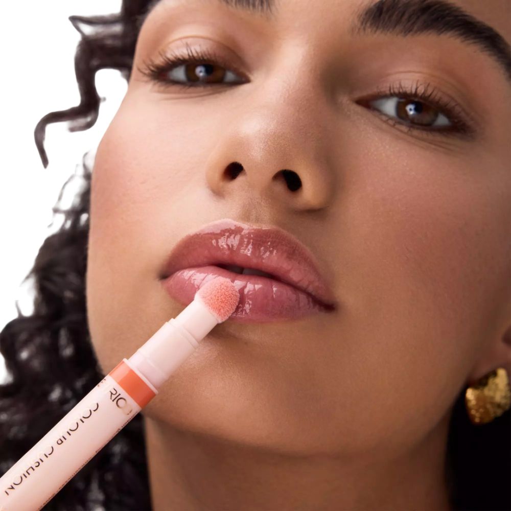 Ein Lippenstiftapplikator mit einem weichen Schwämmchen, der auf die Lippen aufgetragen wird. Der Stift ist hellrosa mit Text.