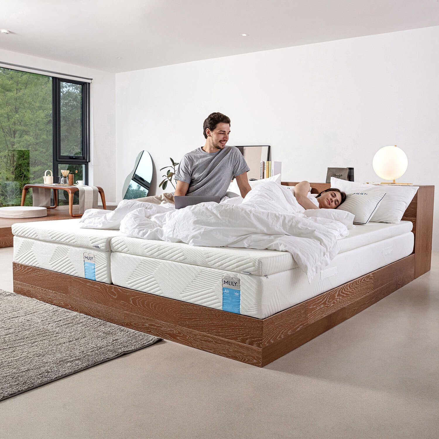 Schlafzimmer mit Doppelbett. Topper auf Matratzen. Paar im Bett.