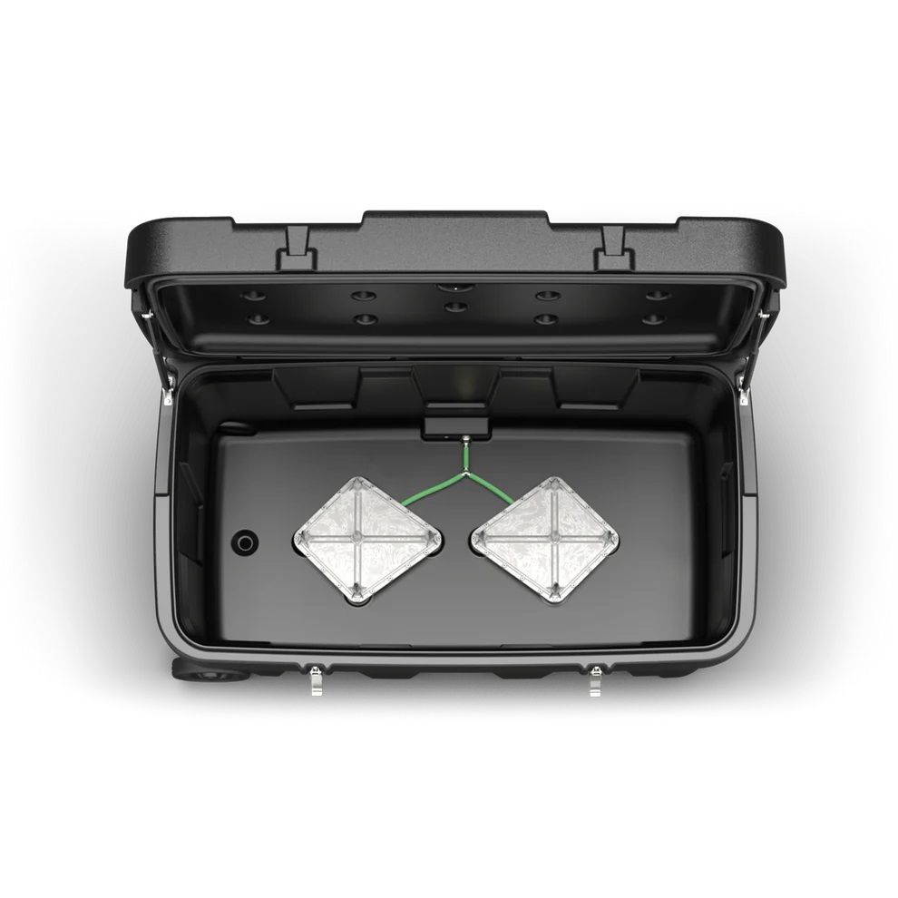 Schwarzer Behälter, geöffnet, mit zwei quadratischen Elementen und grünen Kabeln. Draufsicht.