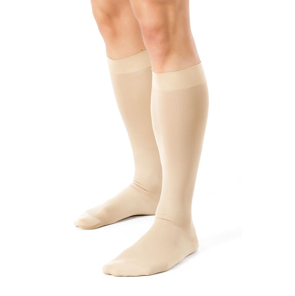 Beige Kompressionsstrümpfe bis zum Knie. Geripptes Material. Auf weißem Hintergrund, Seitenansicht.