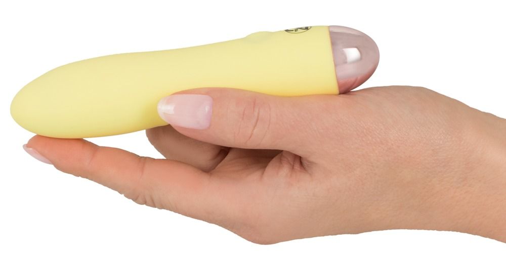 Gelber Vibrator in einer Hand gehalten. Rosa Spitze, glatte Oberfläche.