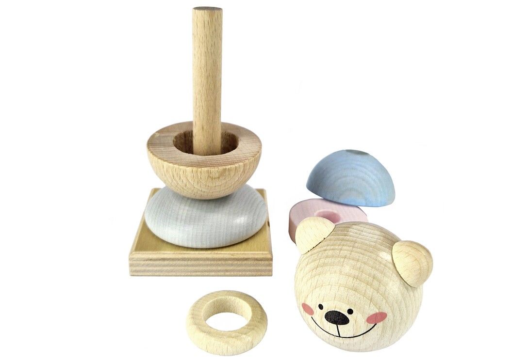 Holzstapelspiel mit Bärenkopf, farbigen Ringen und Kugeln. Einzelteile neben einem Turm.