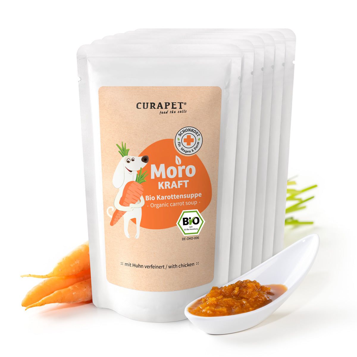 Mehrere Beutel Bio Karottensuppe. Aufdruck: CURAPET, Moro Kraft, Bio Karottensuppe. Mit Karotten, Löffel mit Suppe.