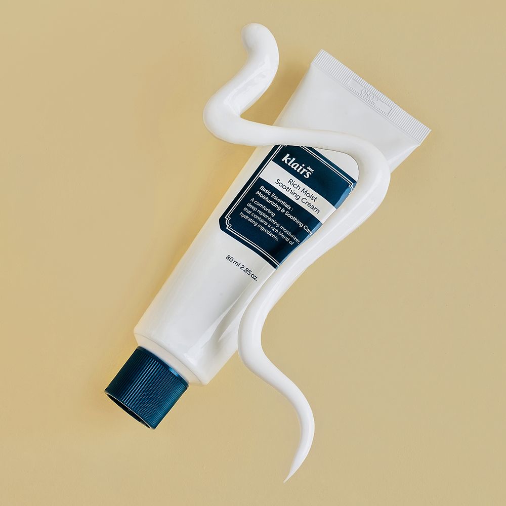 Klairs Rich Moist Soothing Cream Tube, umgeben von einer Schlange aus weißer Creme.