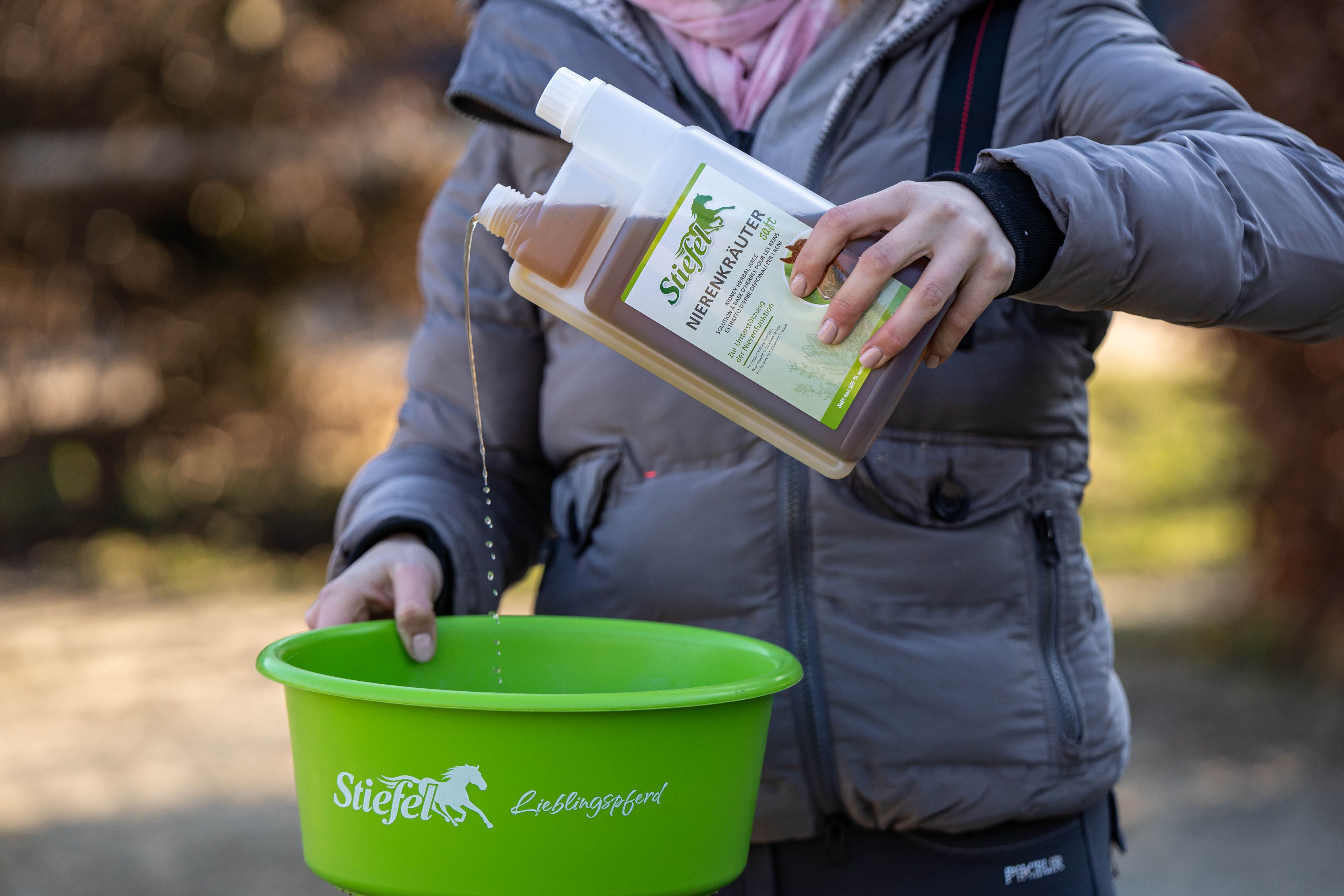 Person gießt Kräutersaft aus einer Flasche in eine grüne Schüssel. Aufschrift auf der Flasche: Stiefel Nierenkräuter Saft.