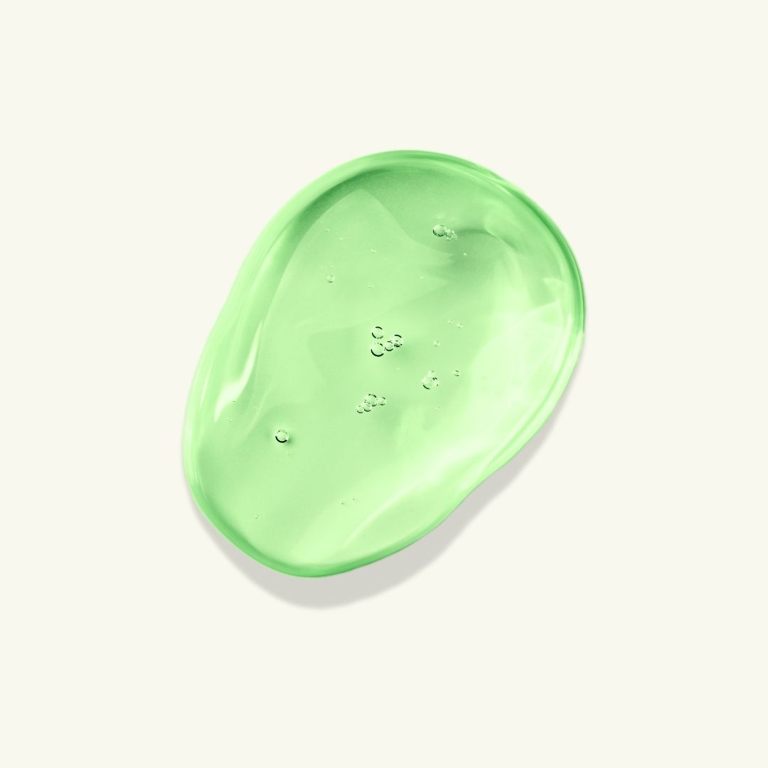 Una goccia di siero verde su sfondo chiaro. La consistenza è gelatinosa e leggermente traslucida, con piccole bolle. È un prodotto per il trattamento delle imperfezioni cutanee.