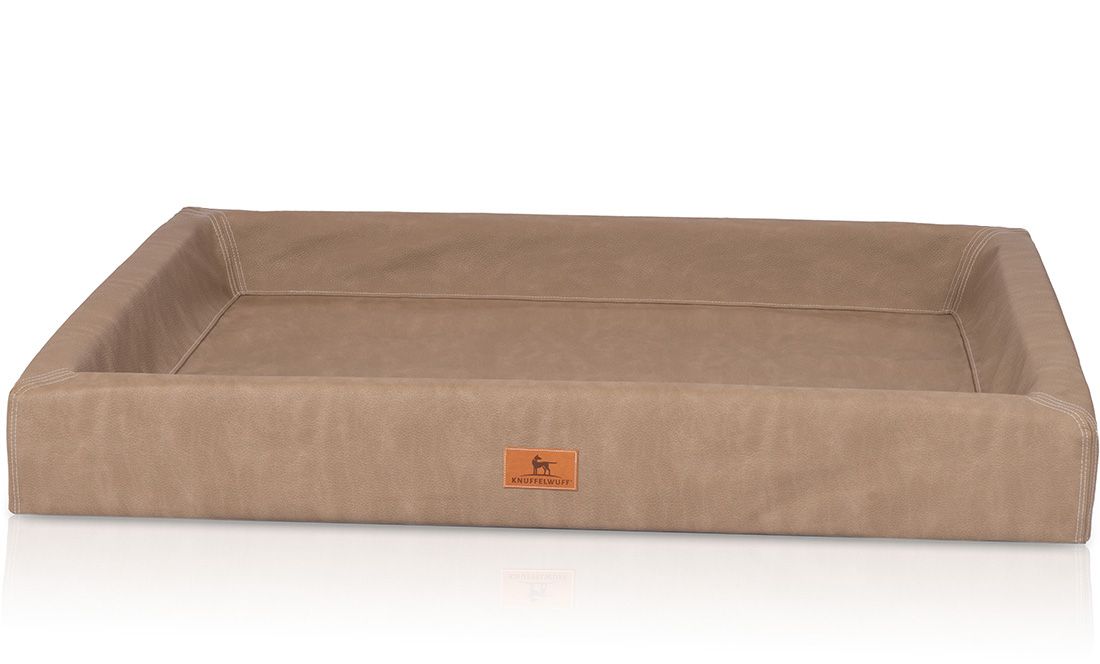 Orthopädisches Hundebett in Beige. Rechteckige Form mit erhöhtem Rand. Logo-Patch an der Vorderseite.