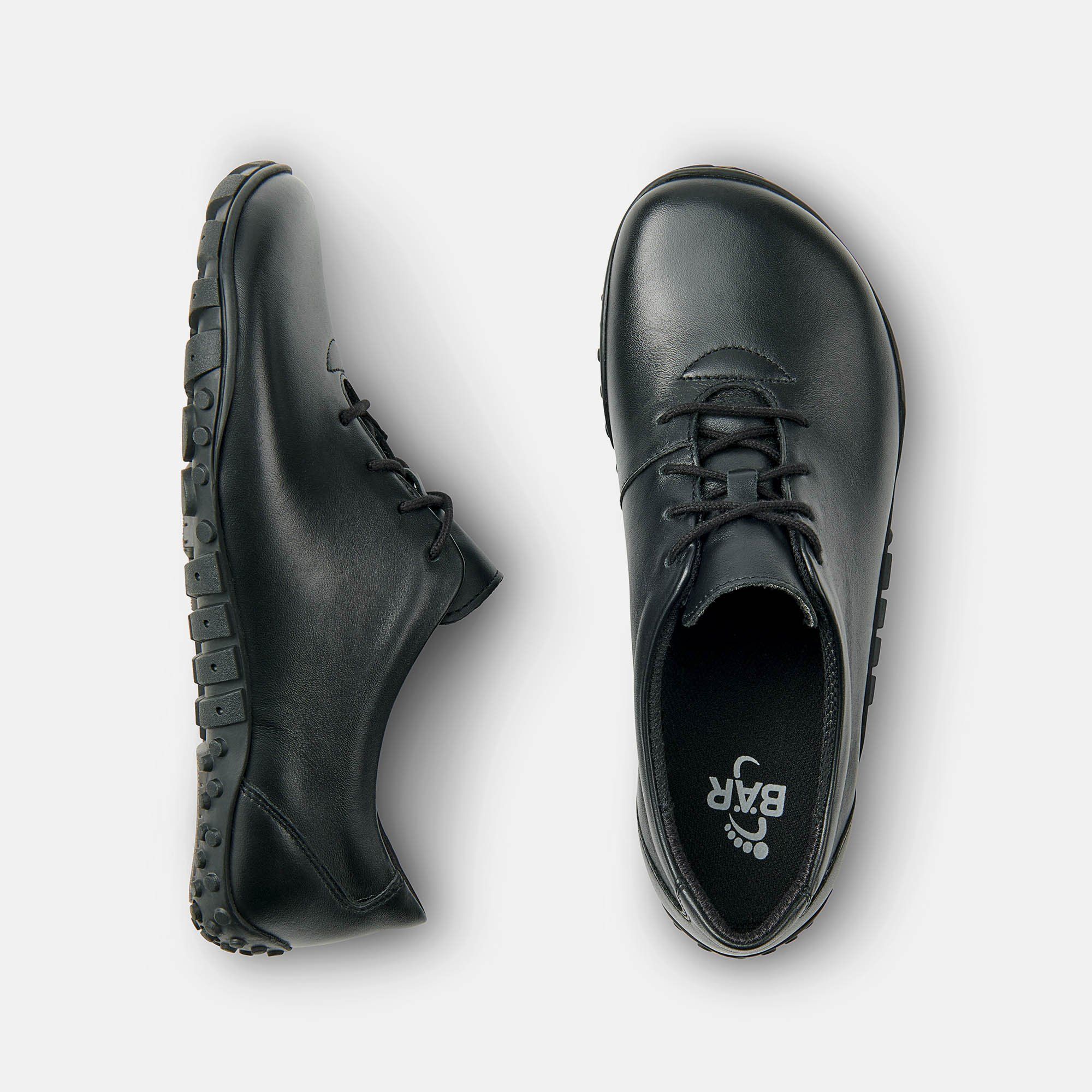 Zwei schwarze Herren-Schnürschuhe. Glattes Leder, Schnürung, breite Passform. Draufsicht, Sohle mit Logo.