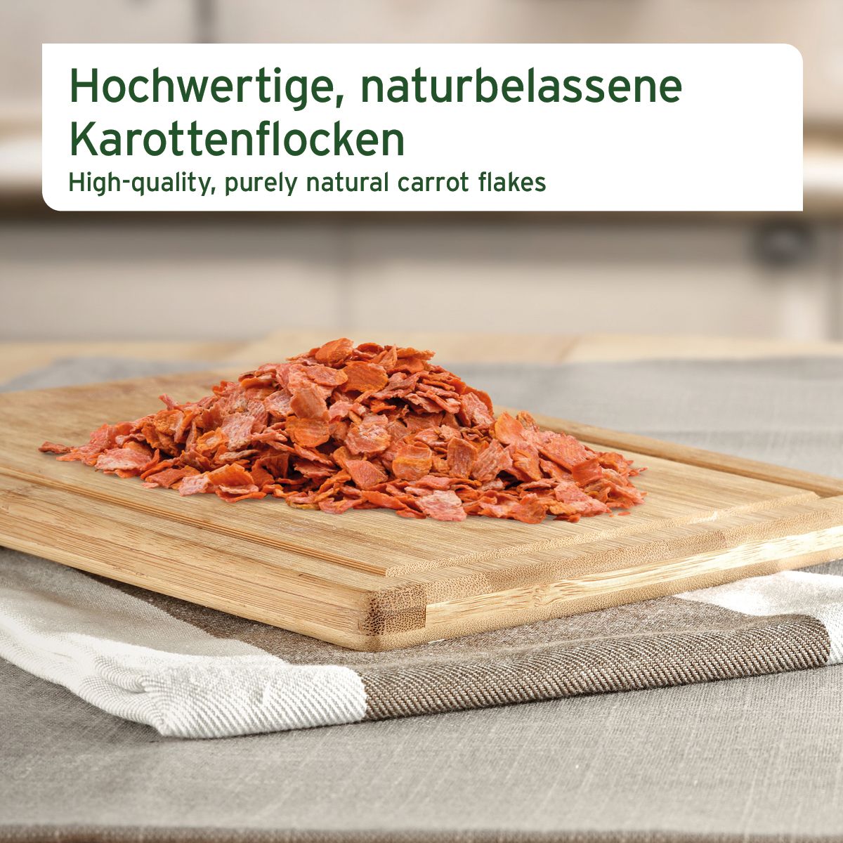 Haufen von Karottenflocken auf einem Holzbrett. Text: Hochwertige, naturbelassene Karottenflocken.