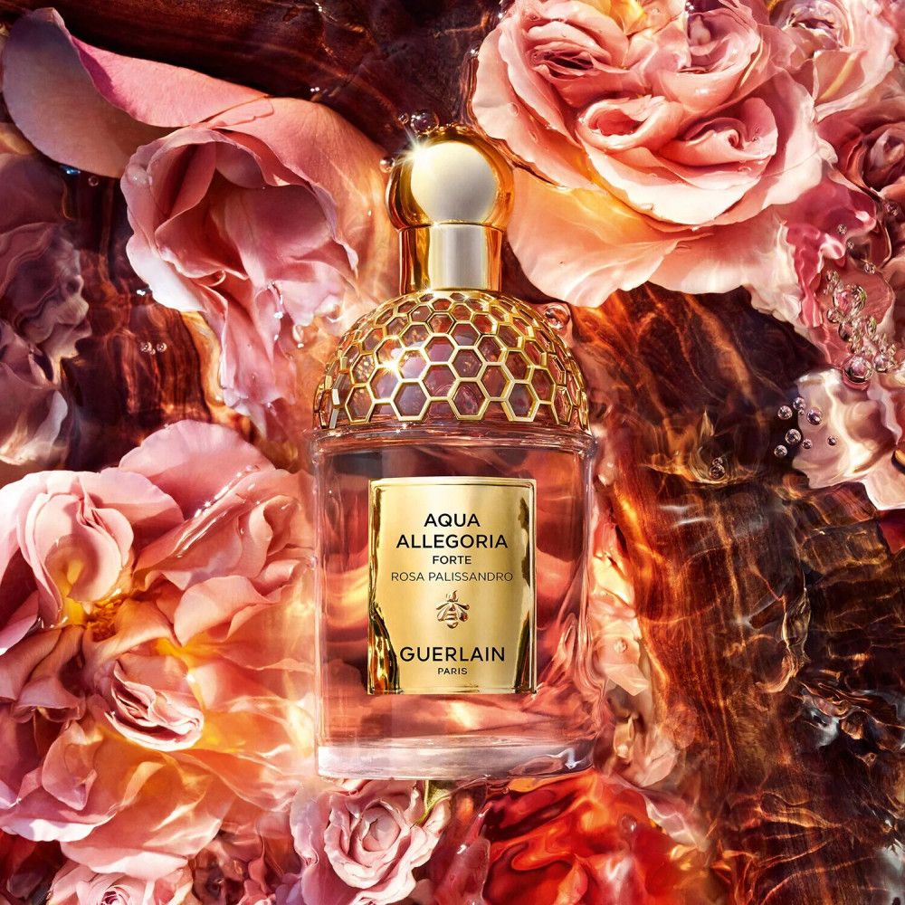 Parfümflakon in Wasser mit Rosenblüten. Goldfarbener Verschluss und Honigwabenmuster. Auf dem Etikett: Aqua Allegoria Forte Rosa Palissandro, Guerlain.