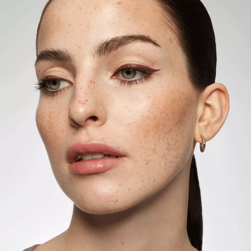 Porträt einer Frau mit braunem Eyeliner. Augenbrauen, Lippen und Haut betont.