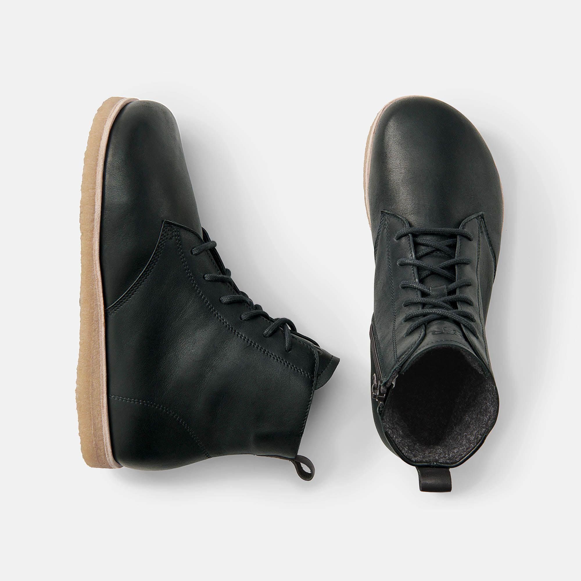 Zwei schwarze Stiefeletten mit Schnürung und beiger Sohle. Draufsicht, eine mit Reißverschluss.