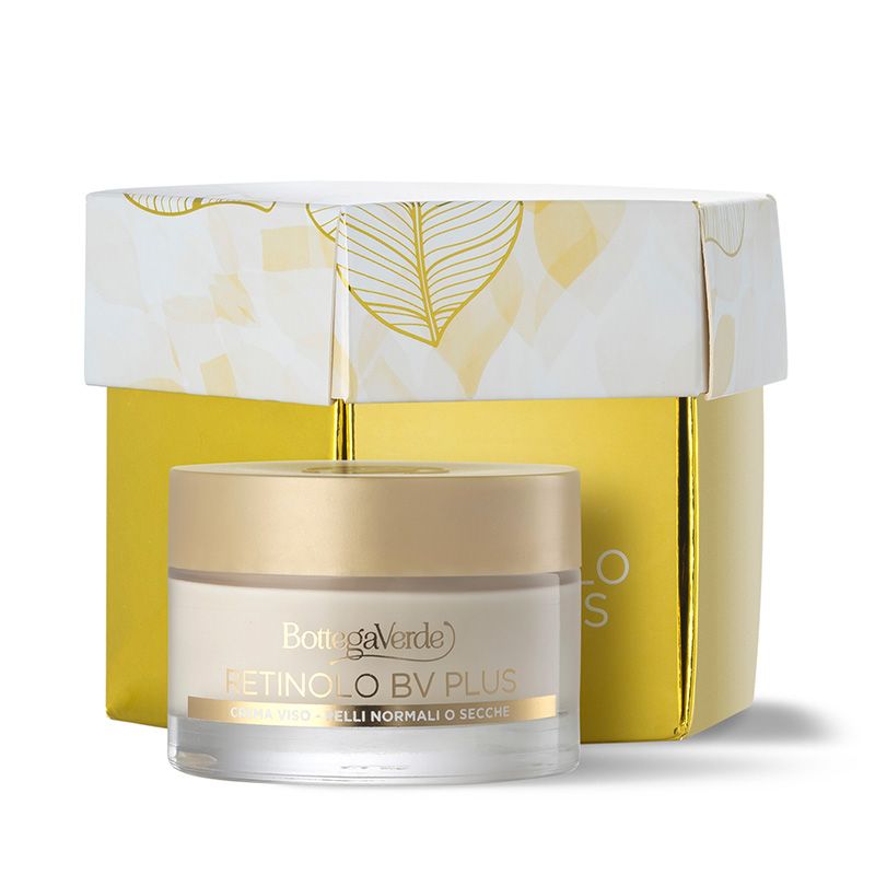 Crema Bottega Verde Scrigno Retinolo in un vasetto di vetro con coperchio dorato. La crema è posta davanti a una confezione regalo gialla con dettagli dorati. Sul vasetto si legge "RETINOLO BV PLUS" e "CREMA VISO PELLI NORMALI O SECCHE".