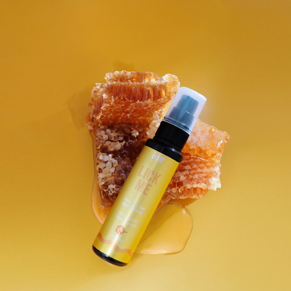 Gelbe Flasche mit schwarzem Sprühkopf. Aufschrift: intt Lick Me, Kissable Gel, Warm Effect, Honey. Honigwabe daneben.